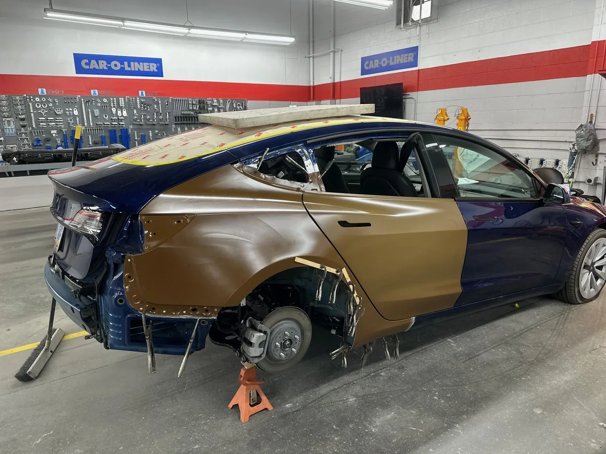 A Tesla with rear-quarter bodywork exposed during repair at E3
