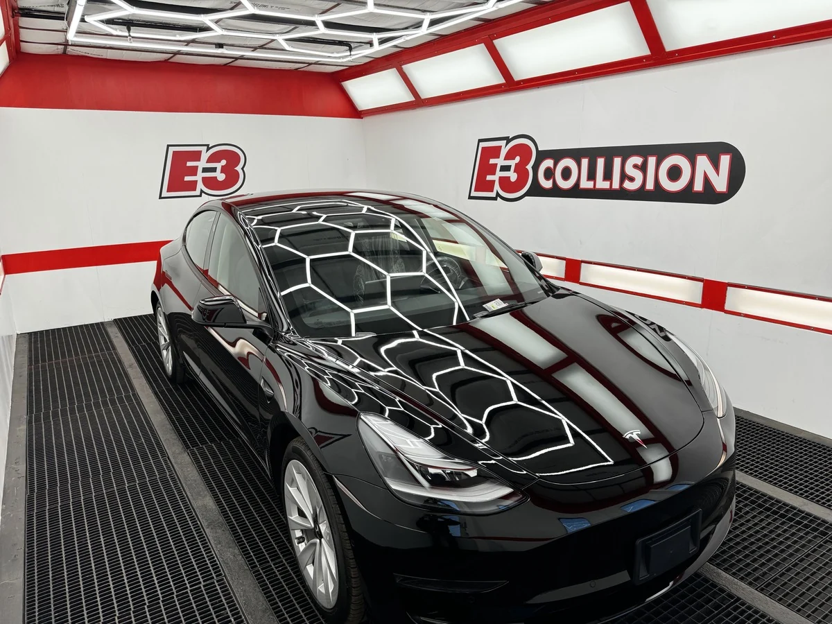 Black Tesla beneath the geometric inspection lights at E3 Collision